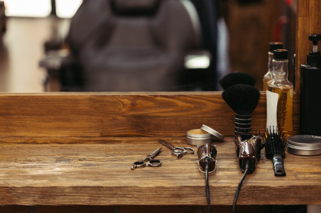 barber tools on wooden shelf and mirror in barbershop e1610348490961