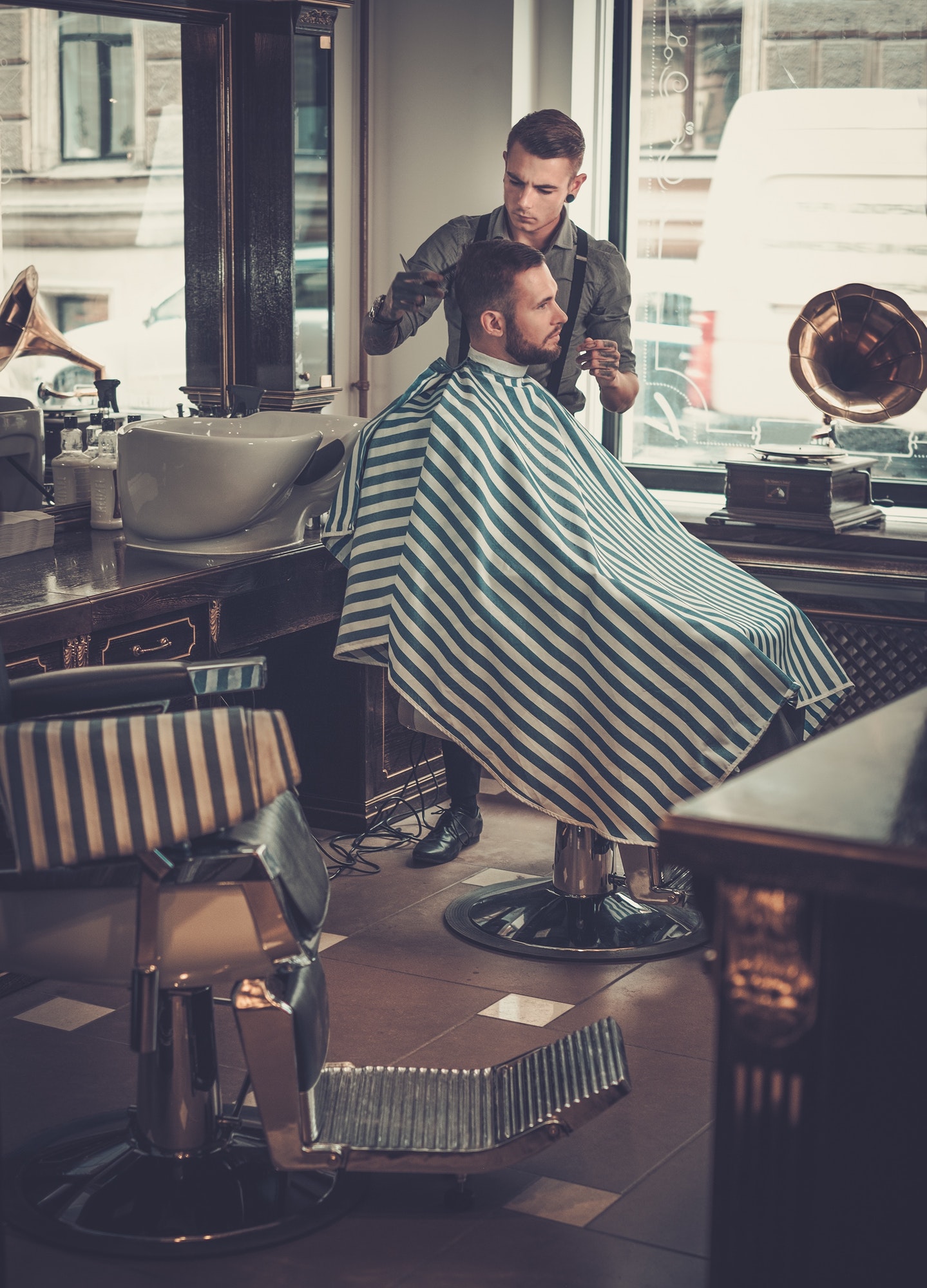 confident man visiting hairstylist in barber shop